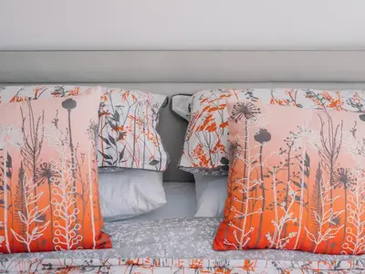 two pillows on a bed with orange and gray sheets at Pentire in Saint Minver