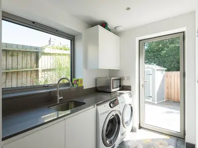 a kitchen with a sink and a washing machine at Pentire in Saint Minver