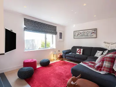 a living room with a couch and a red rug at Pentire in Saint Minver