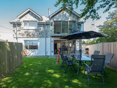 a patio with a table and chairs and an umbrella at Pentire in Saint Minver