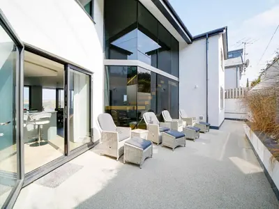 a row of white chairs sitting on a patio at Megizzy in Polzeath