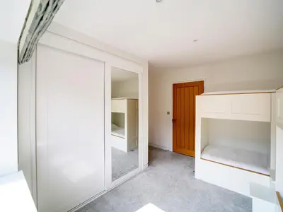 a bedroom with white cabinets and a mirror at Megizzy in Polzeath