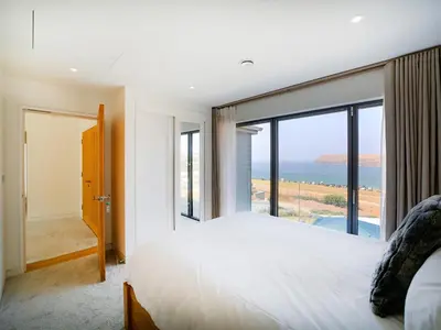 a bedroom with a bed and a view of the ocean at Megizzy in Polzeath