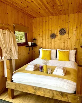 a bedroom with a bed in a wooden room at Trethowels Hidden Huts in St Austell