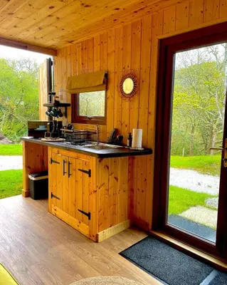 a kitchen in a log cabin with a window at Trethowels Hidden Huts in St Austell
