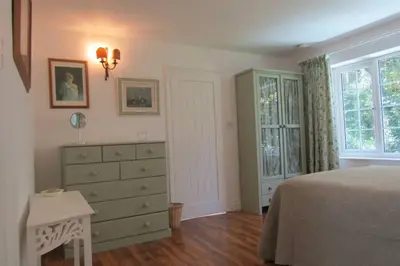 a bedroom with a bed and a dresser and a window at Lovely Spacious Cottage Near The Coast in St Austell