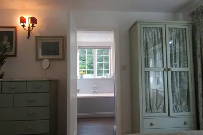 a bedroom with a bath tub and a window at Lovely Spacious Cottage Near The Coast in St Austell