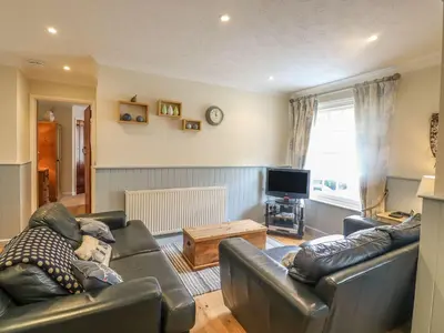a living room with two leather couches and a television at Olde Carpenters Cottage in Boscastle