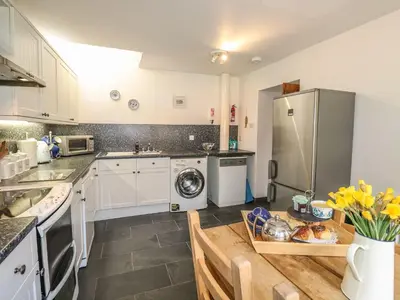 a kitchen with white cabinets and a refrigerator at Olde Carpenters Cottage in Boscastle