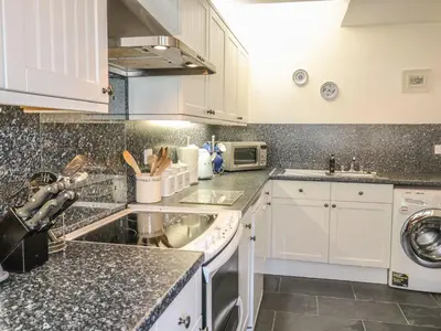 a kitchen with white cabinets and a sink at Olde Carpenters Cottage in Boscastle