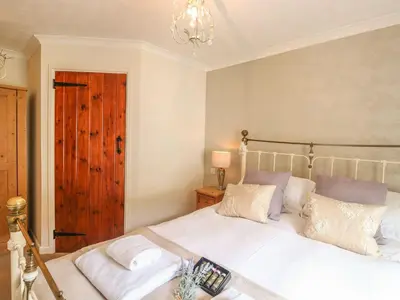 a bedroom with a white bed and a chandelier at Olde Carpenters Cottage in Boscastle
