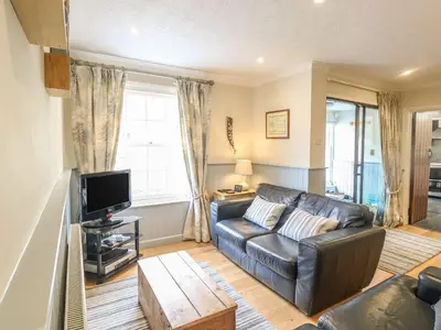 a living room with a leather couch and a tv at Olde Carpenters Cottage in Boscastle