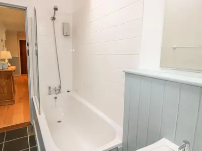 a white bath tub in a bathroom with a window at Olde Carpenters Cottage in Boscastle
