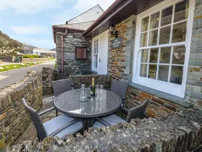a patio with a table and chairs in front of a building at Olde Carpenters Cottage in Boscastle