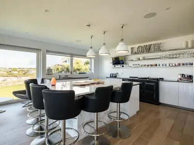 a kitchen with a large island with black bar stools at Seascape in Polzeath