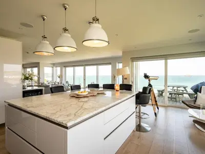 a kitchen with a large island with a view of the ocean at Seascape in Polzeath