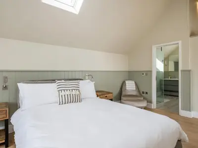 a bedroom with a white bed and a chair at Seascape in Polzeath