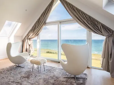 a living room with two white chairs and a large window at Seascape in Polzeath