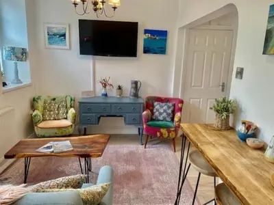 a living room with two chairs and a tv at St Ives apartment private parking with garden 10 minute walk into town and beach in St Ives