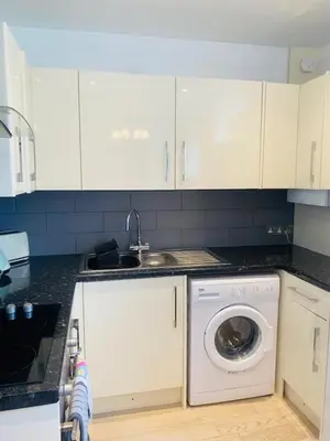 a kitchen with a washing machine and a sink at St Ives apartment private parking with garden 10 minute walk into town and beach in St Ives