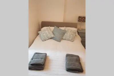 a bed with two towels and pillows on it at St Ives apartment private parking with garden 10 minute walk into town and beach in St Ives