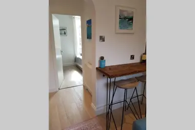 a kitchen with a table and stools in a room at St Ives apartment private parking with garden 10 minute walk into town and beach in St Ives
