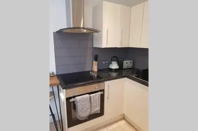 a kitchen with white cabinets and black counter tops at St Ives apartment private parking with garden 10 minute walk into town and beach in St Ives