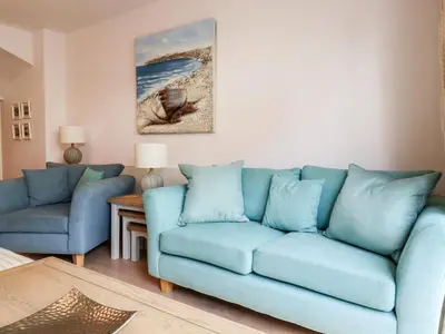 a living room with a blue couch and a table at 16 Ocean Heights in Newquay