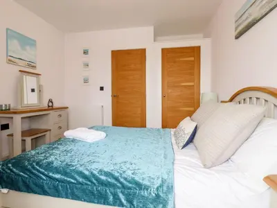 a bedroom with a white bed with a blue blanket at 16 Ocean Heights in Newquay