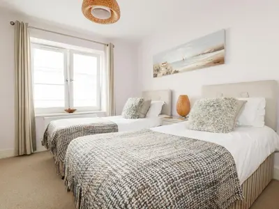 two beds in a bedroom with white walls and a window at 16 Ocean Heights in Newquay