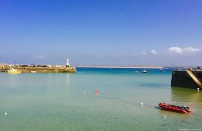a red boat sitting in the water near a pier at Little Chyryn Perranuthnoe in Perranuthnoe