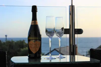 a bottle of wine and two wine glasses on a table at Little Chyryn Perranuthnoe in Perranuthnoe