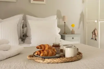 a tray of croissants and coffee on a bed at Swallow Cottage in Port Isaac