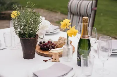 a white table with a bottle of wine and flowers at Swallow Cottage in Port Isaac