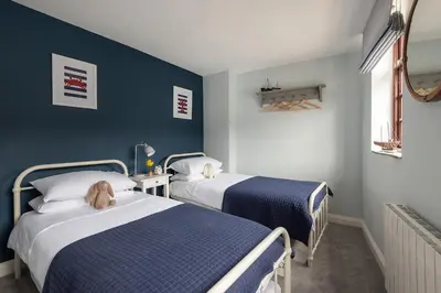 two beds in a room with blue walls at Swallow Cottage in Port Isaac