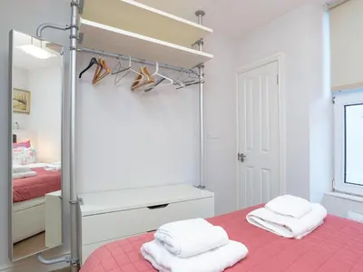 a bedroom with a pink bed and a mirror at Apartment 2 The Wheelhouse in Fowey