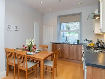 a kitchen and dining room with a wooden table and chairs at Apartment 2 The Wheelhouse in Fowey