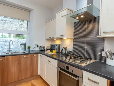 a kitchen with white cabinets and a stove top oven at Apartment 2 The Wheelhouse in Fowey