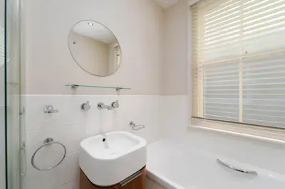 a white bathroom with a sink and a mirror at Tregarth in St Ives
