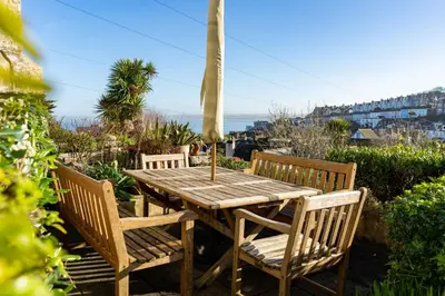 a wooden table with two chairs and an umbrella at Tregarth in St Ives