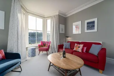 a living room with red couches and a table at Tregarth in St Ives
