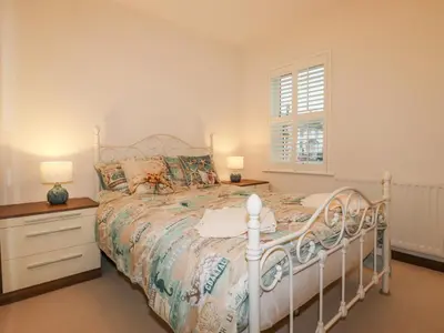 a bedroom with a white bed and a window at 1 Old Talbot Cottages in Lostwithiel