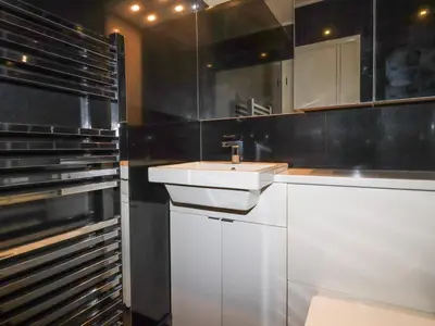 a bathroom with a white sink and a black wall at 1 Old Talbot Cottages in Lostwithiel