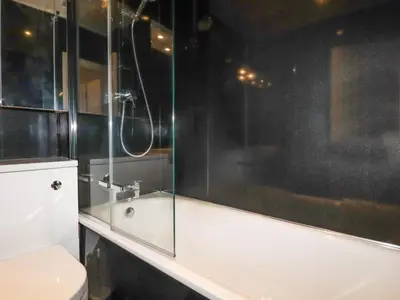 a bathroom with a tub and a glass shower at 1 Old Talbot Cottages in Lostwithiel