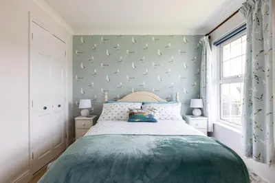 a bedroom with a bed and a wall with birds on it at Gulland in Port Isaac
