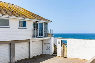 a house with a garage and the ocean in the background at Gulland in Port Isaac