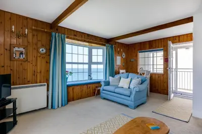 a living room with a blue couch and windows at Gulland in Port Isaac