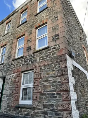 a brick building with windows on the side of it at Triple Deck Cottage - 2mins from Mevagissey Harbour in Mevagissey