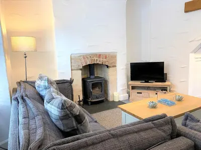 a living room with a couch and a fireplace at Triple Deck Cottage - 2mins from Mevagissey Harbour in Mevagissey