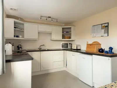 a white kitchen with white cabinets and appliances at Sea Glimpses in Port Isaac